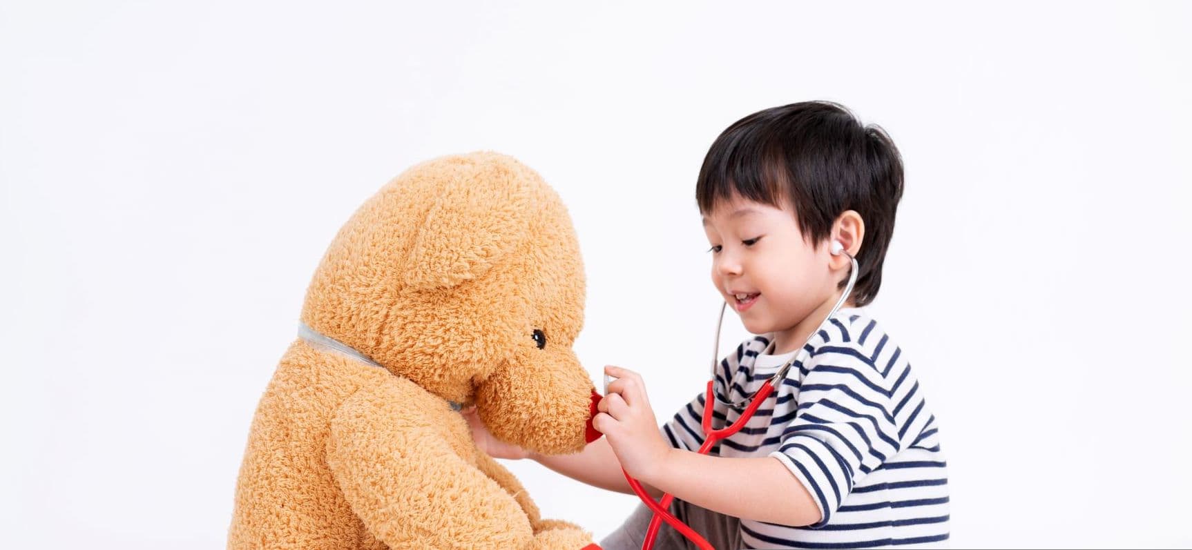 niño con estetoscopio de juguete jugando al doctor con sus oso de peluche